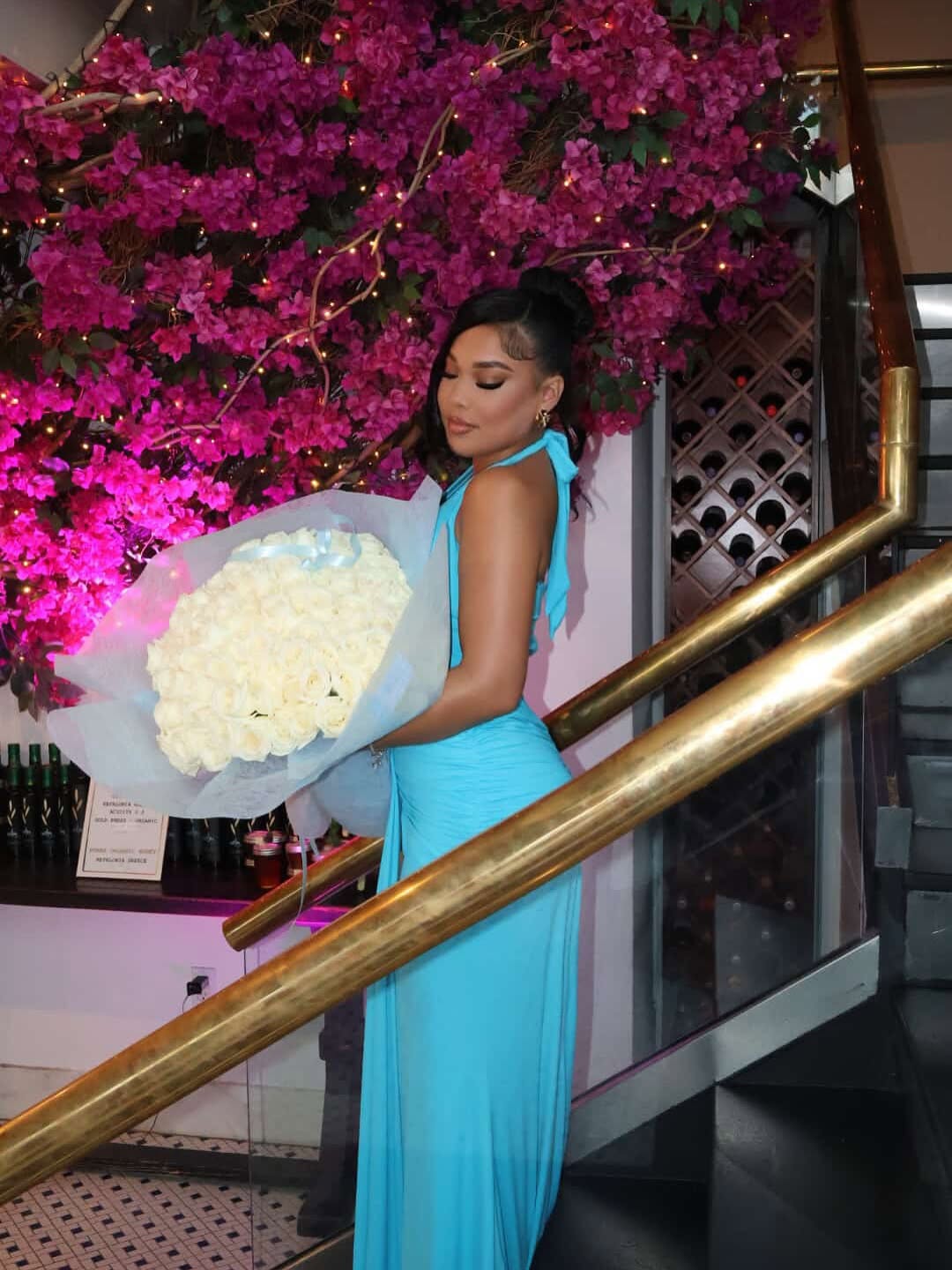 Client with white roses on staircase with floral backdrop