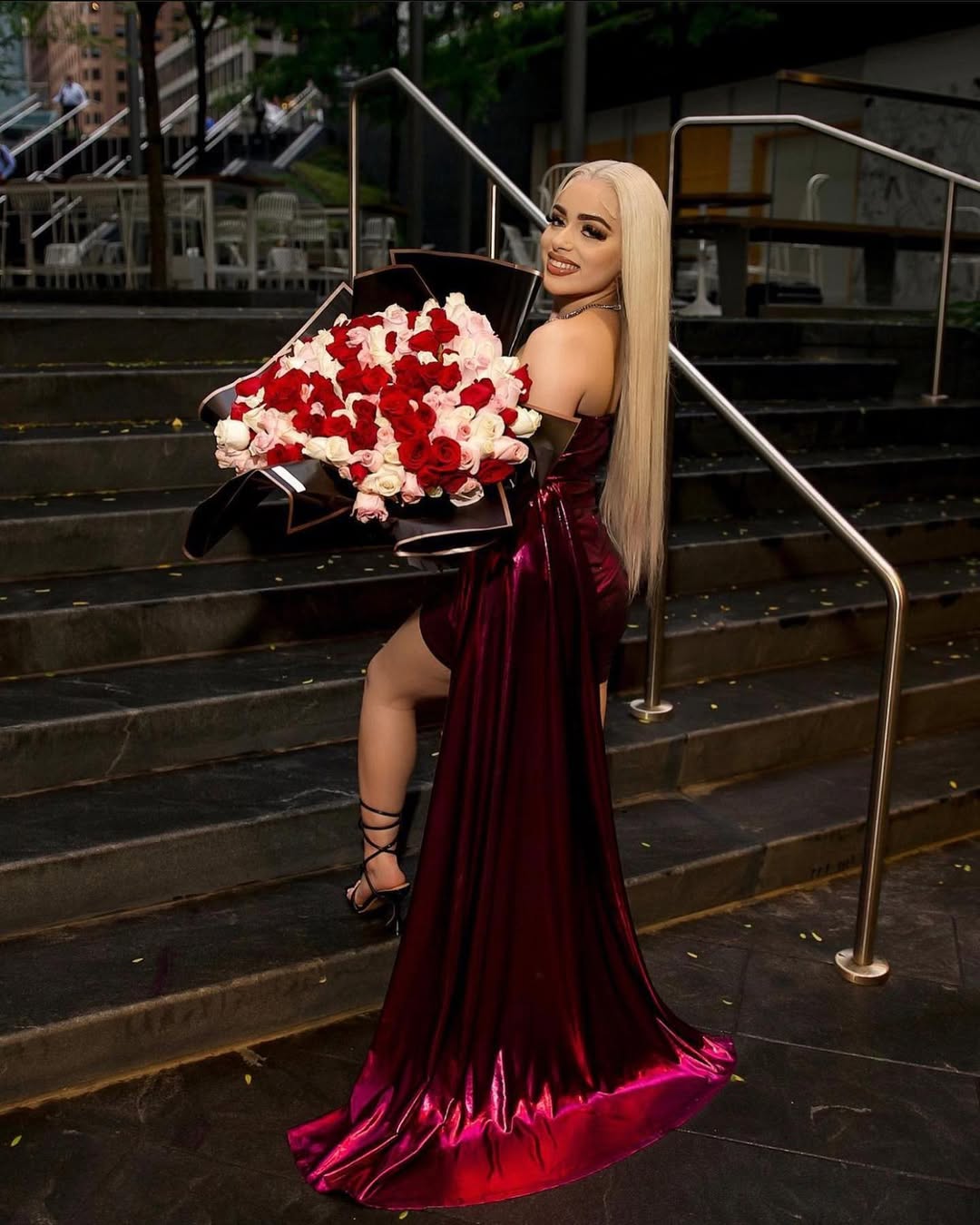 Client elegantly posing with pink roses on outdoor staircase